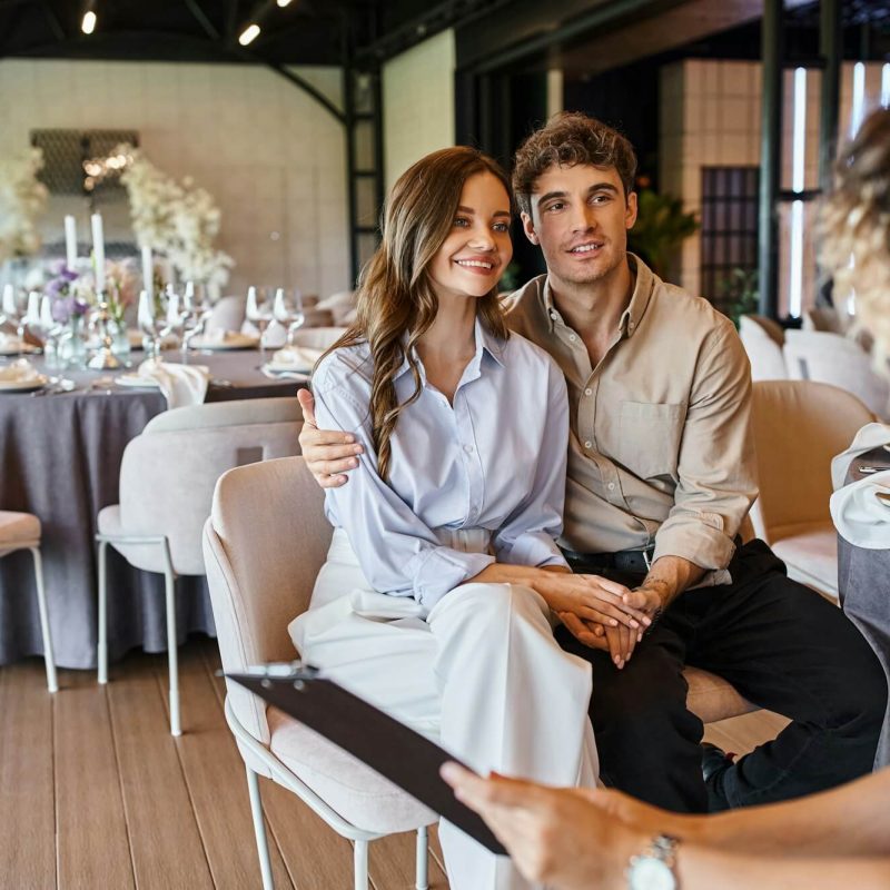 banquet-organizer-with-clipboard-talking-to-couple-in-love-in-event-hall-with-wedding-decor.jpg banquet-organizer-with-clipboard-talking-to-couple-in-love-in-event-hall-with-wedding-decor.jpg